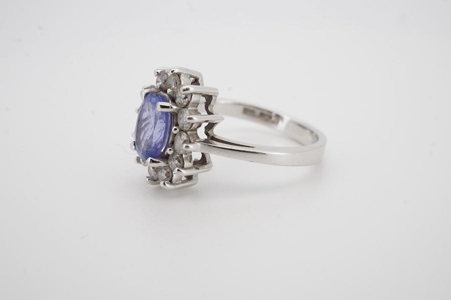 A modern 14k white metal, tanzanite and diamond set oval cluster ring, size M, gross weight 4.3 grams.